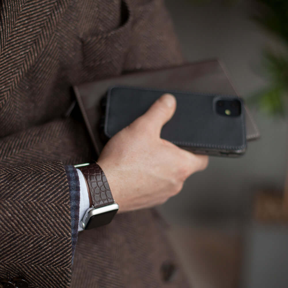 Strap for the Apple Watch 45/46 mm in brown matte alligator leather, with steel adapters and buckle | lifestyle photo, the strap worn on a man's wrist