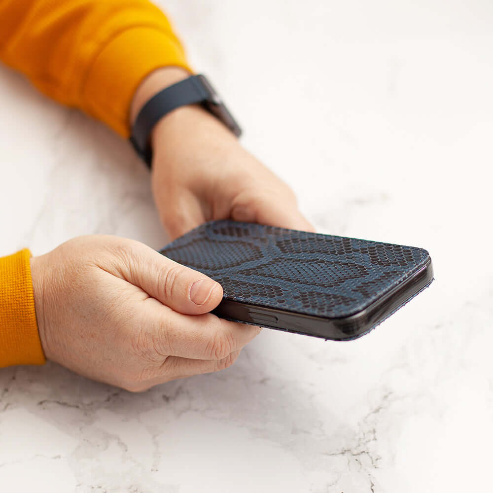 Person holding an iPhone 17 Pro Max Python Blue Leather Case on a marble surface.
