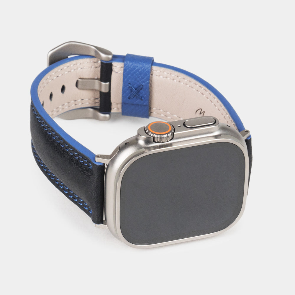 Men's Apple Watch Ultra band 49mm in black smooth calfskin leather with blue edge finish and its titanium color adapters - front dial view