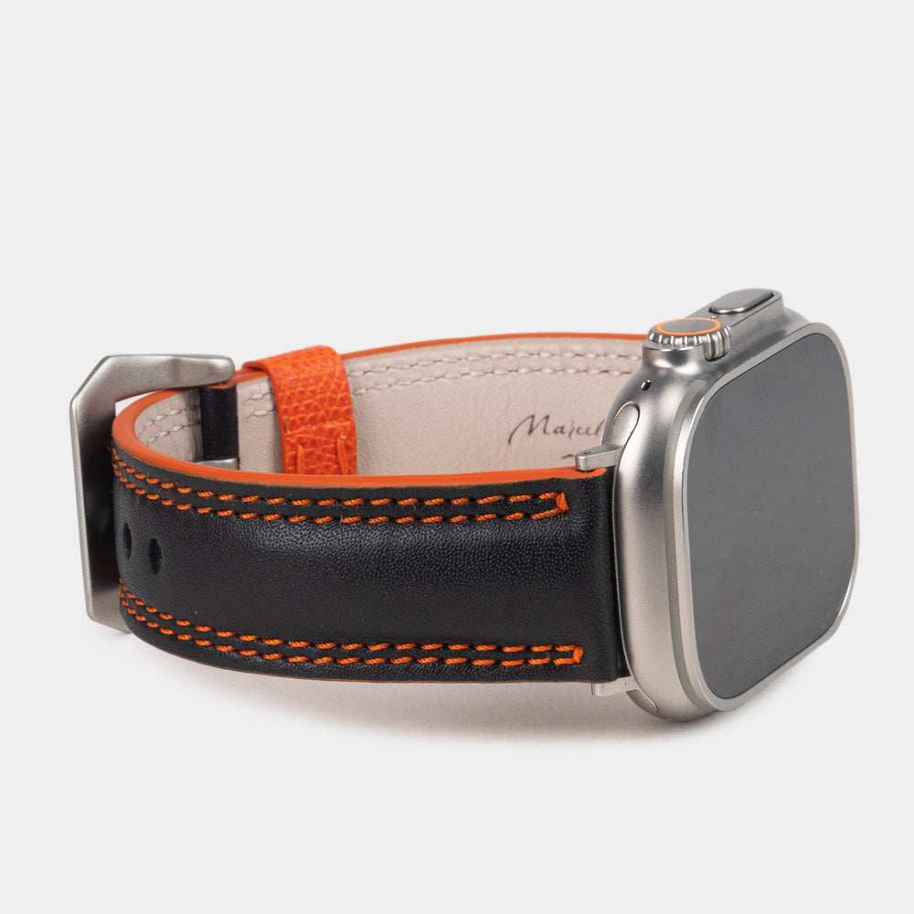 Men's Apple Watch Ultra band 49mm in black smooth calfskin leather with orange edge finish and its titanium color adapters - 3/4 profile view