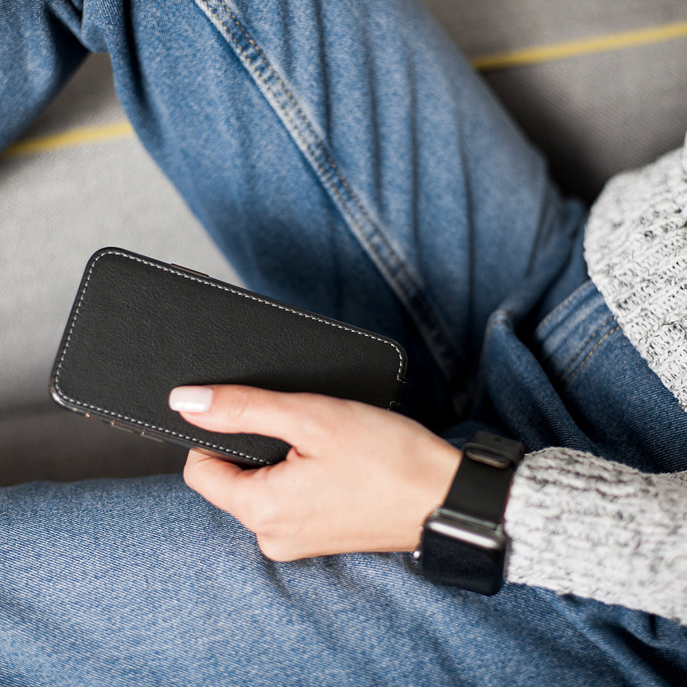 Black leather flip case for iPhone SE in woman's hand, sitting cross-legged
