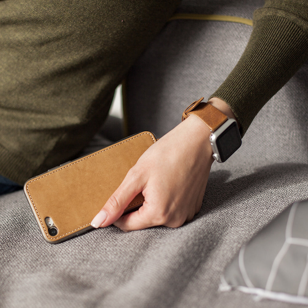 Vintage leather flip case for iPhone SE in woman's hand, resting on a sofa