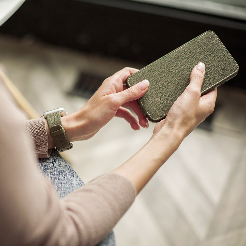 Green leather flip case for iPhone XS Max in woman's hands, opening the cover
