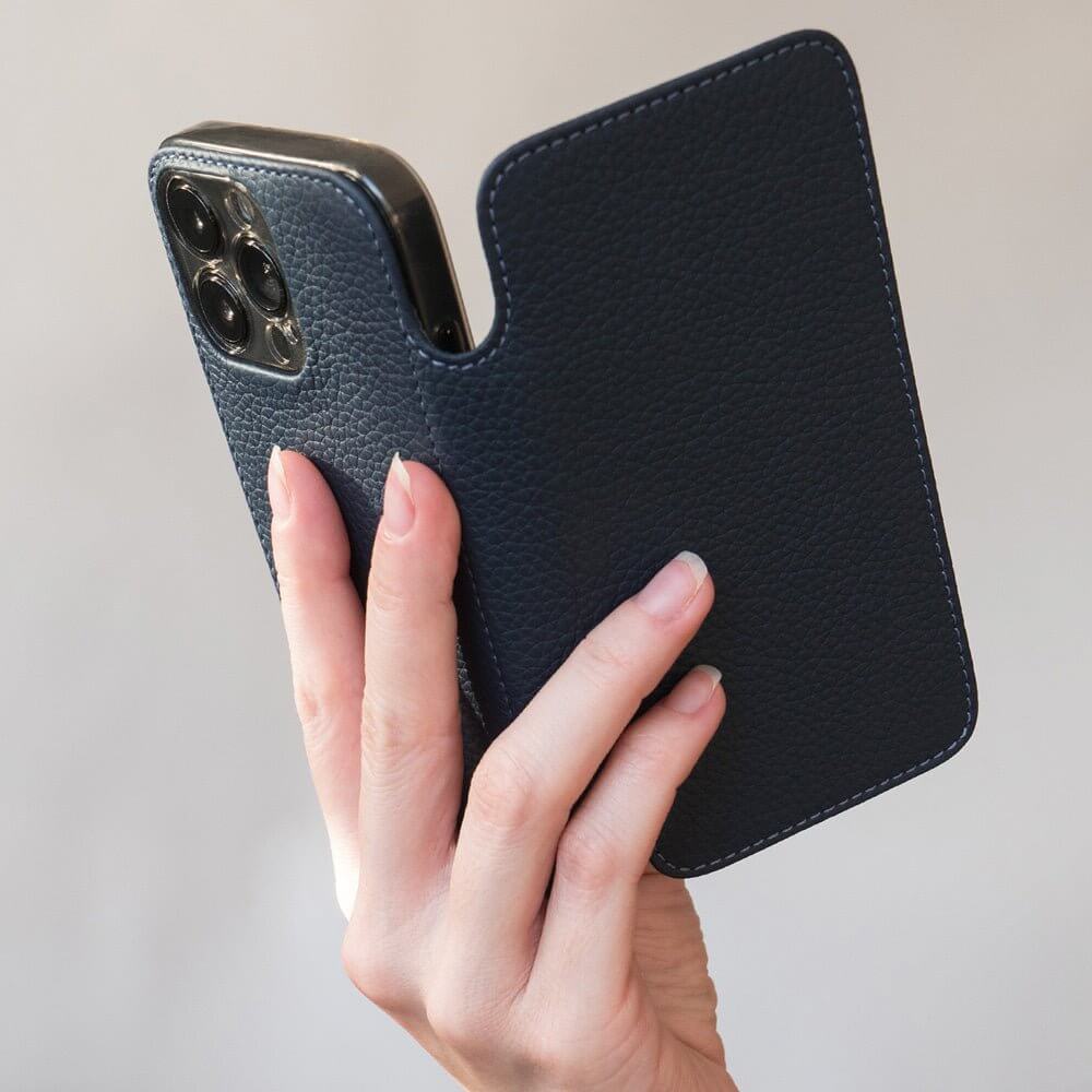 Hand holding a phone in blue leather case against a neutral background