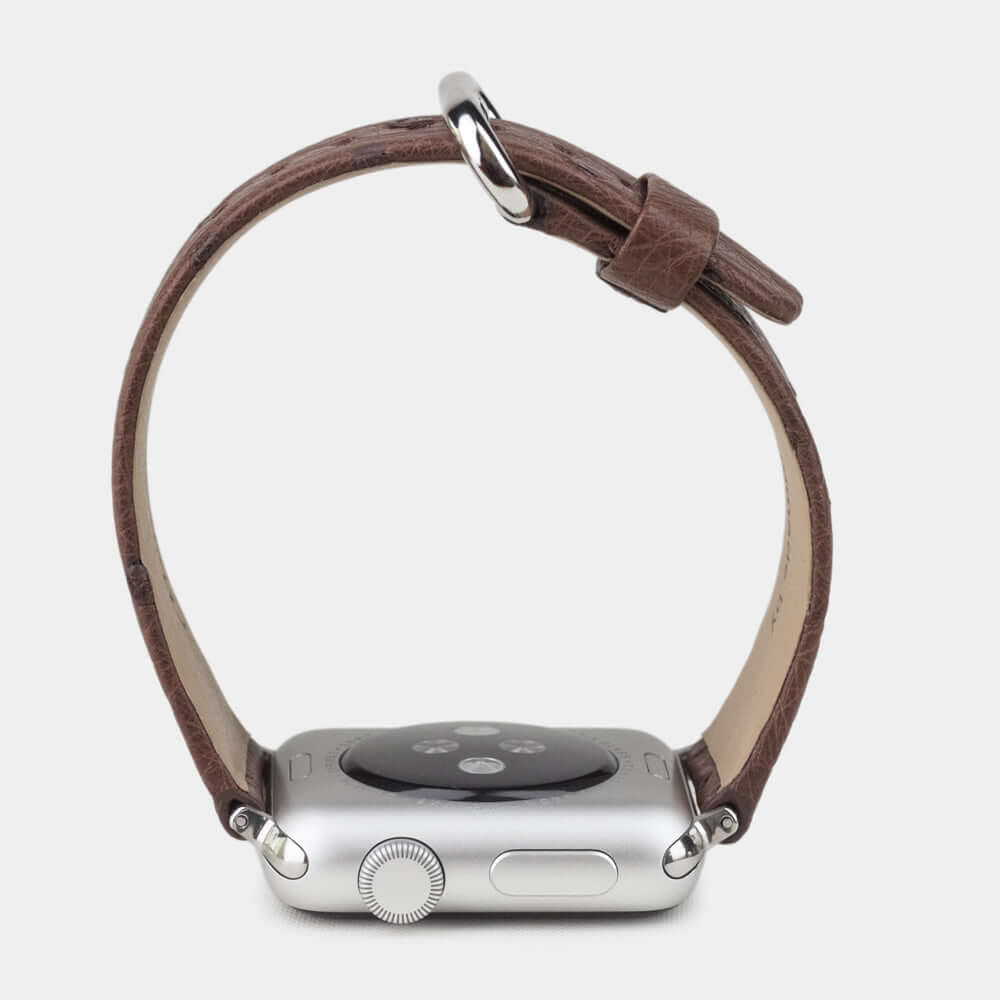Strap for the Apple Watch 41/42 mm in brown ostrich leather, with steel adapters and buckle | watch case on bottom to see leather texture, inner lining and the buckle