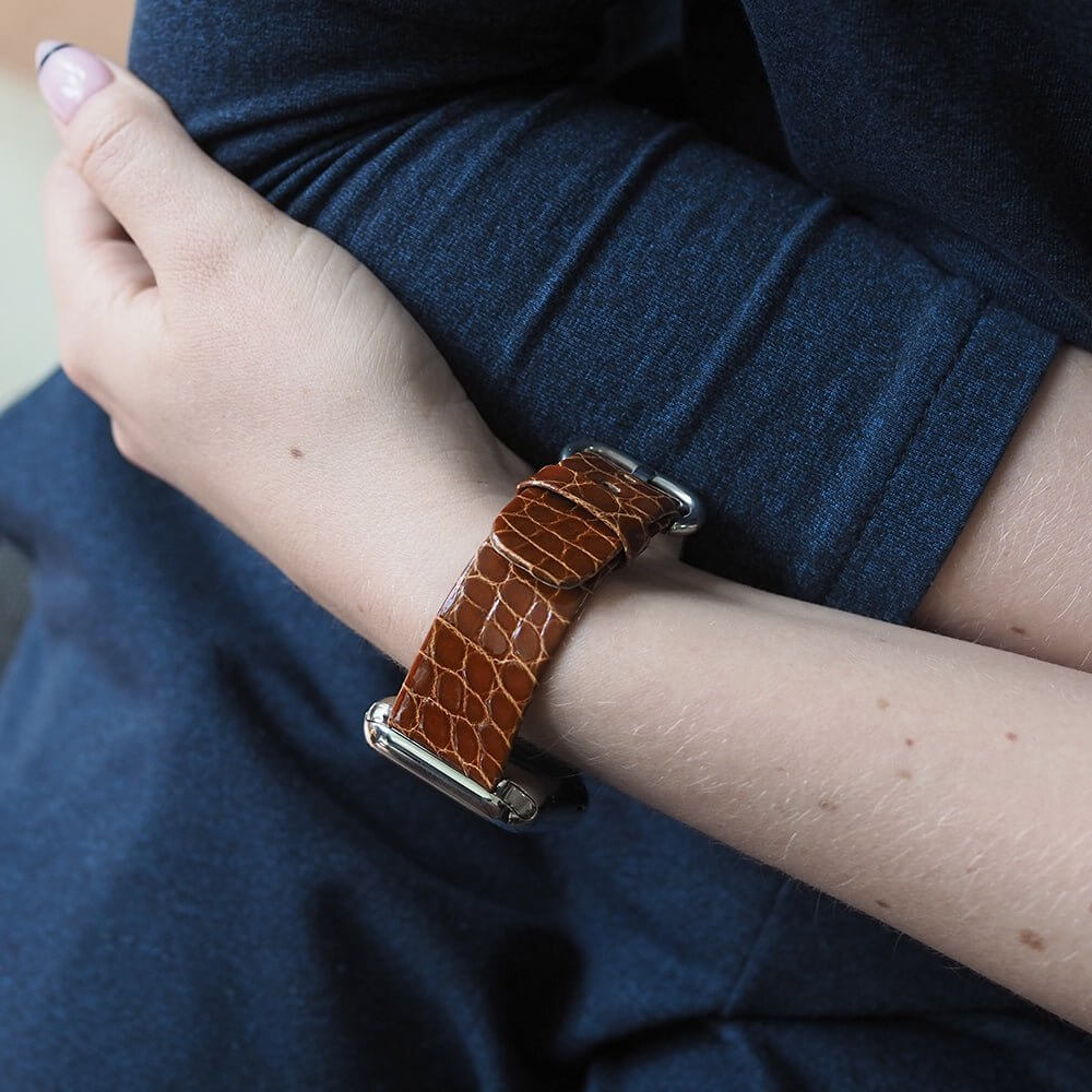 Strap for the Apple Watch 45/46 mm in Gold shiny alligator leather, with steel adapters and buckle | lifestyle photo, the strap worn on a woman's wrist