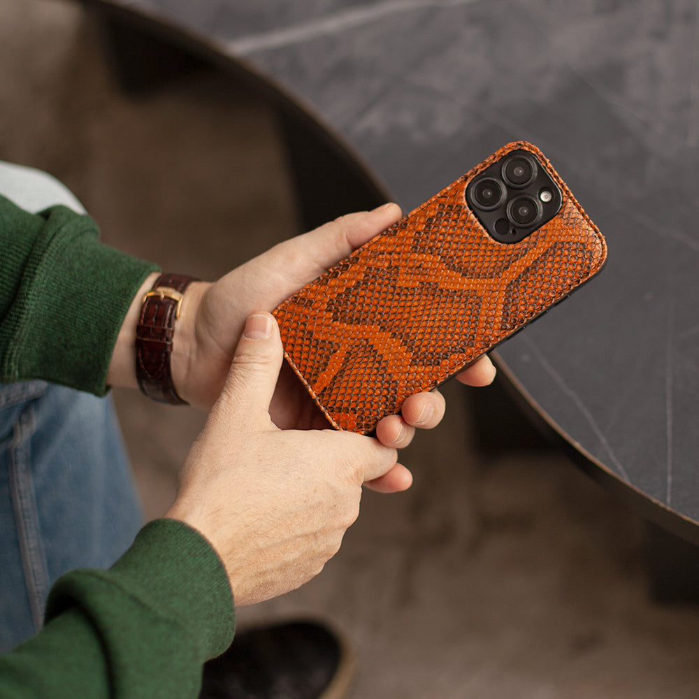 Gold python leather cover case for iPhone 15 Pro held in both hands, showing the scale texture