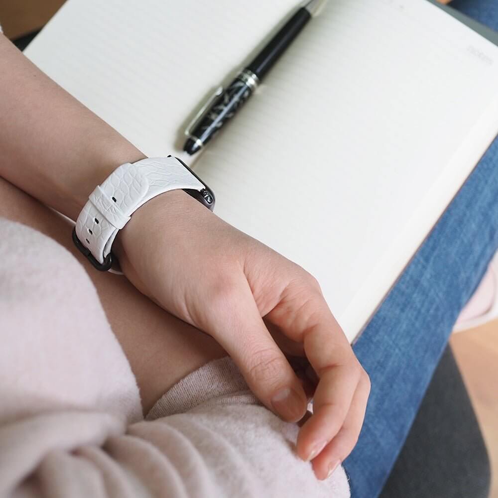 Strap for the Apple Watch 45/46 mm in white matte alligator leather, with black adapters and buckle | lifestyle photo, the strap worn on a woman's wrist