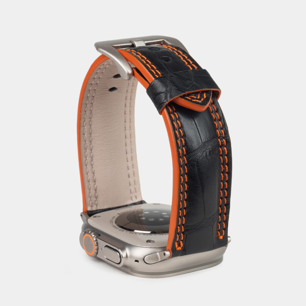Apple Watch Ultra 49 mm in black alligator leather with orange stitching and edge, with titanium adapters and buckle | close view of the square scales, the orange double stitching