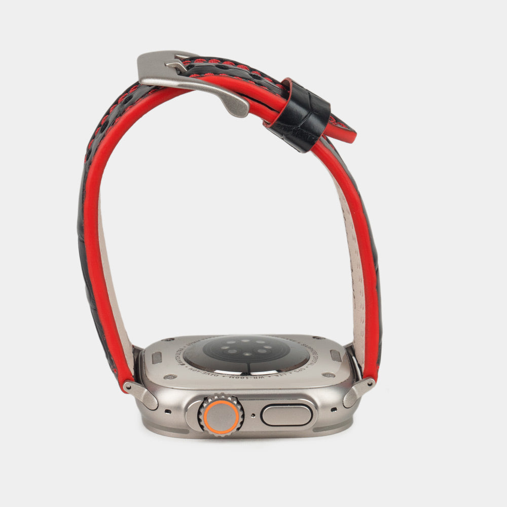 Apple Watch Ultra 49 mm in black alligator leather with red stitching and edge, with titanium adapters and buckle | watch case on bottom to see the red dyed edge