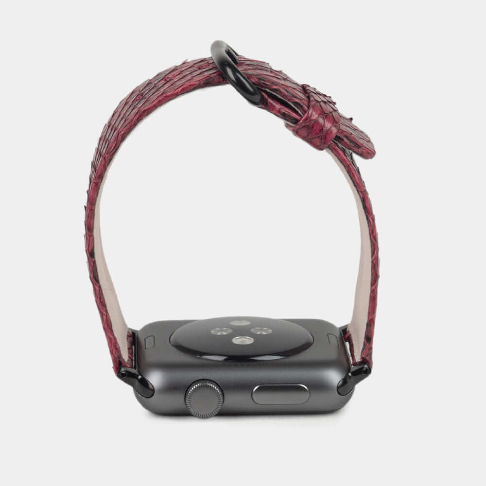 Strap for the Apple Watch 41/42 mm in bordeaux python leather, with black adapters and buckle | watch case on bottom to see leather texture, inner lining and the buckle