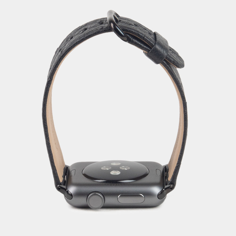 Strap for the Apple Watch 41/42 mm in black ostrich leather, with black adapters and buckle | watch case on bottom to see leather texture, inner lining and the buckle