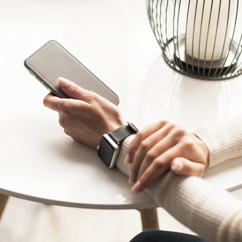 Grey Stone leather flip case for iPhone SE in woman's hand, at a table