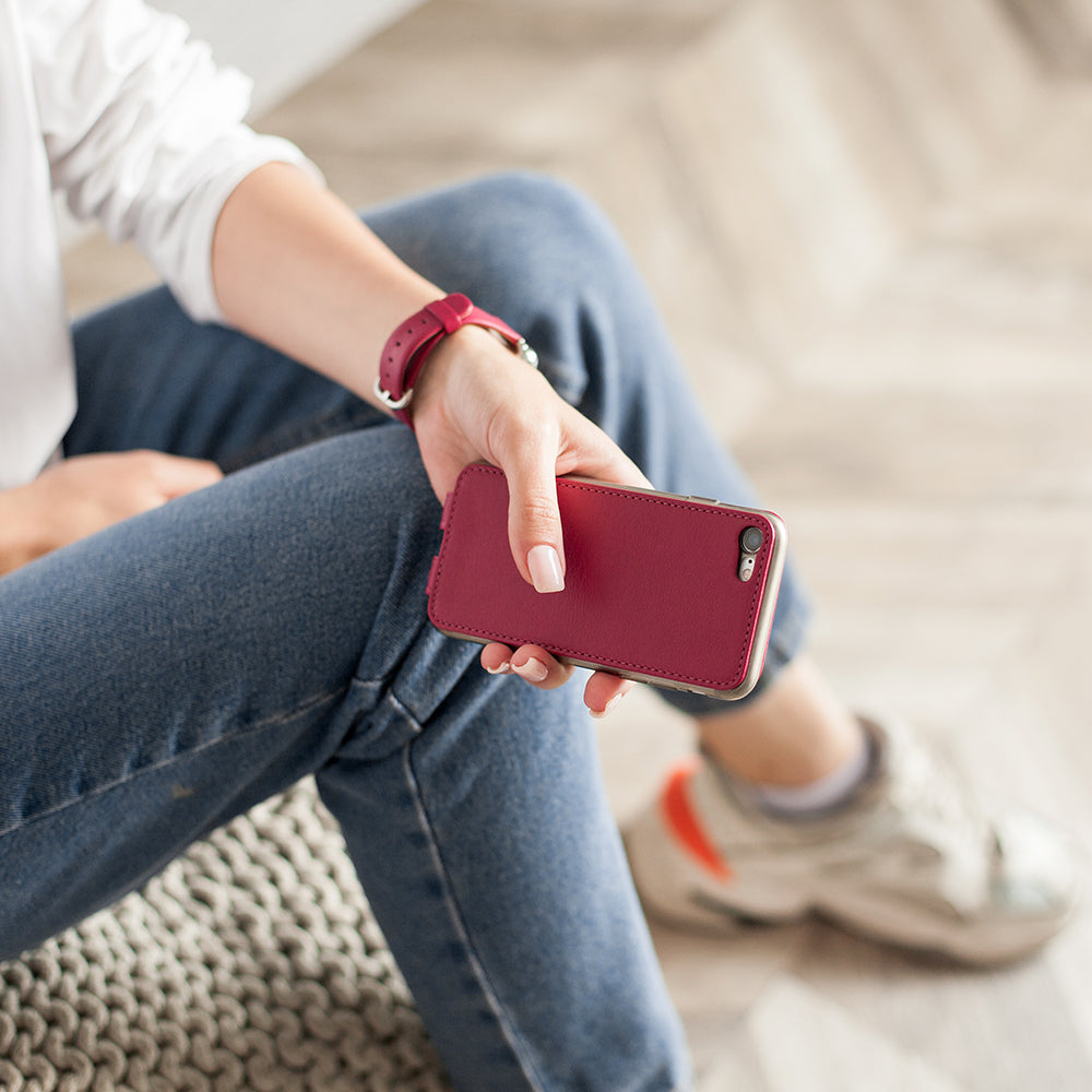 Fuchsia leather flip case for iPhone SE in woman's hand, sitting cross-legged