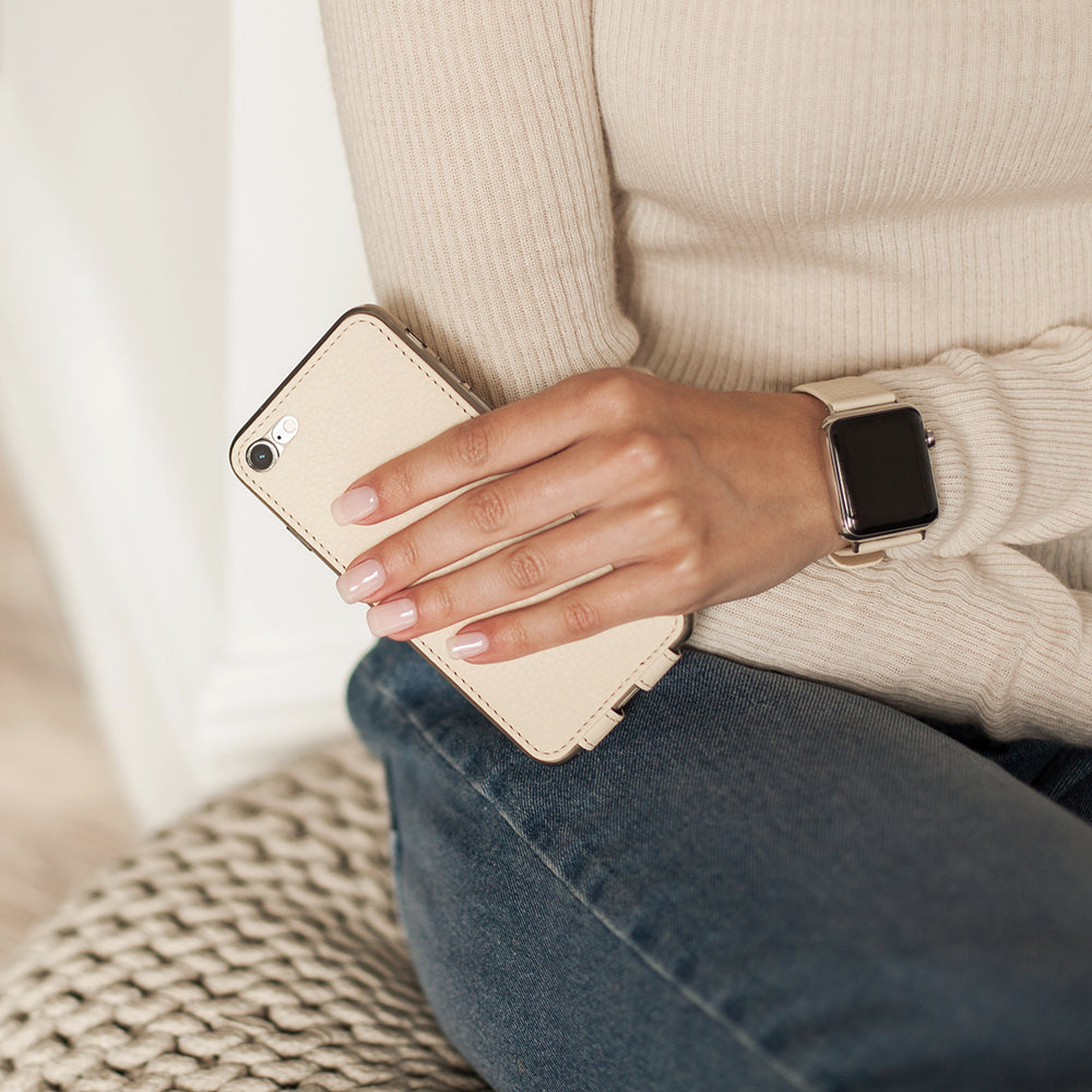 Cream leather flip case for iPhone SE in woman's hand, held against her sweater