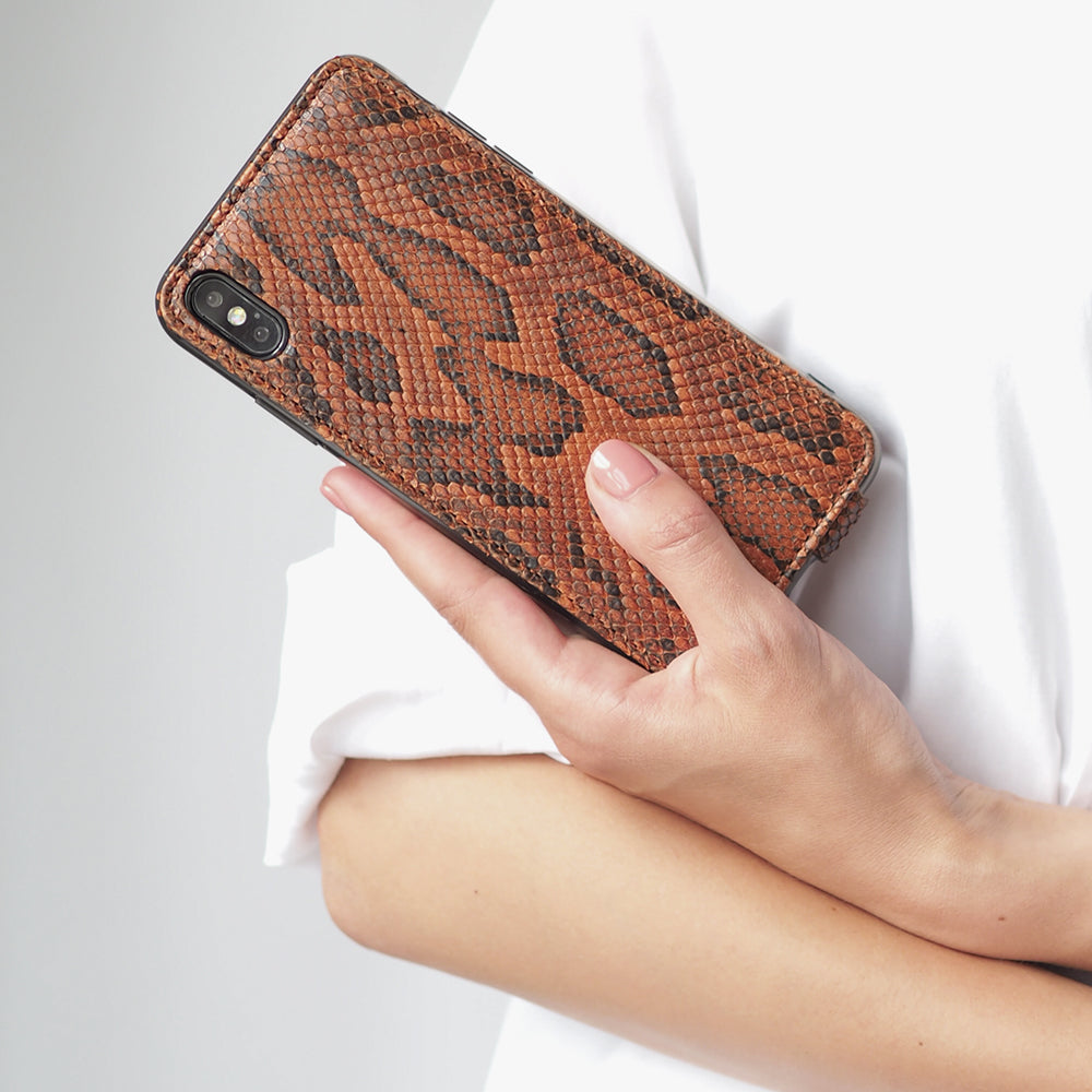 Gold python leather flip case for iPhone XS Max in woman's hand, close-up against a white shirt