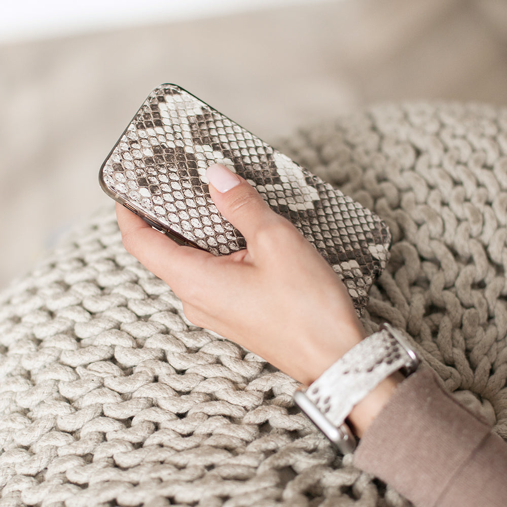 Natural python leather flip case for iPhone X in woman's hand, close-up resting on a knit blanket