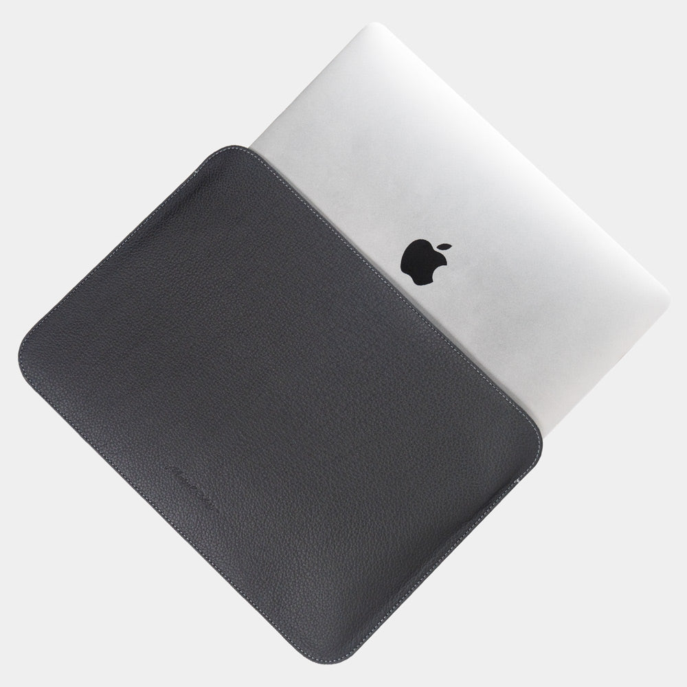 Black 14 inch leather MacBook sleeve with MacBook partially inserted, slim minimalist laptop case for men