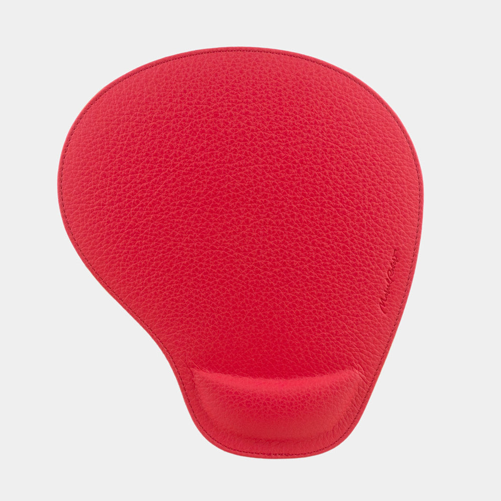Red leather mouse pad seen from above, teardrop shape and embossed signature