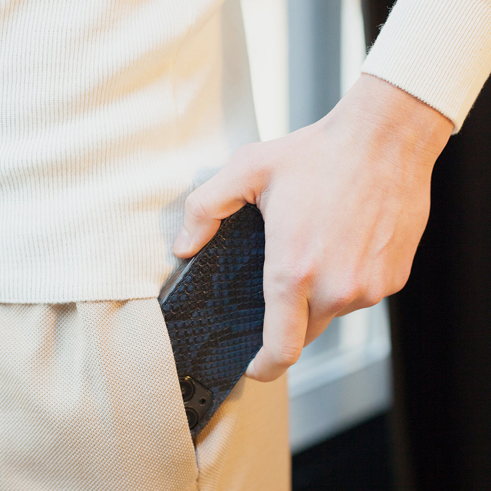 Blue python leather flip case for iPhone 15 Pro slipped into a jacket pocket