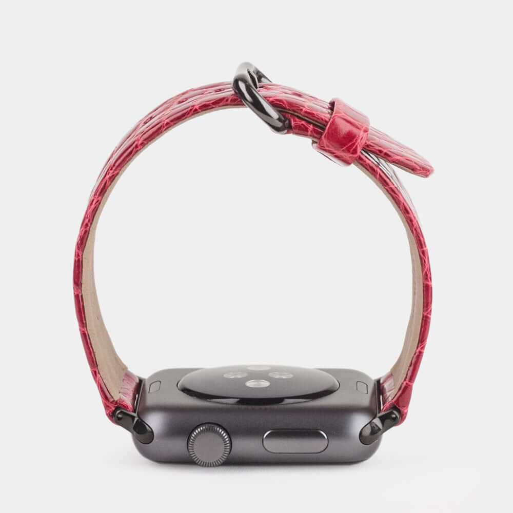 Strap for the Apple Watch 45/46 mm in red shiny alligator leather, with black adapters and buckle | watch case on bottom to see leather texture, inner lining and the buckle
