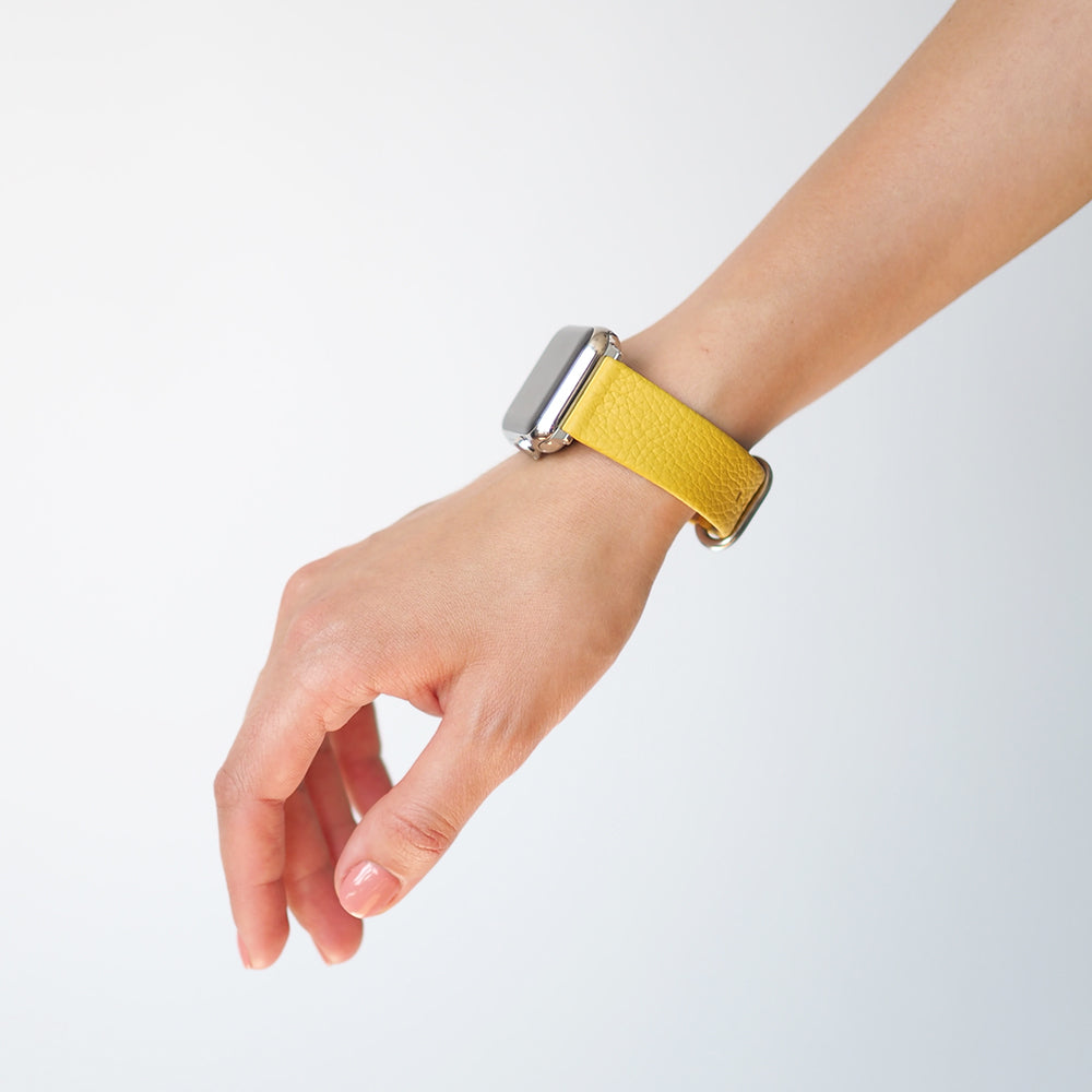 Strap for the Apple Watch 41/42 mm in yellow soft grained calfskin leather, with steel adapters and buckle | lifestyle photo, the strap worn on a woman's wrist