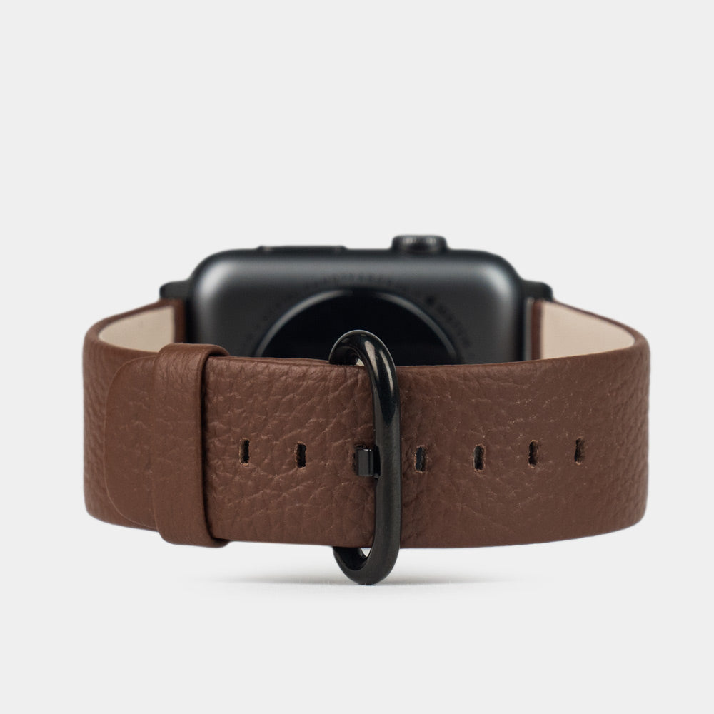 Strap for the Apple Watch 41/42 mm in brown soft grained calfskin leather, with black adapters and buckle | watch case on bottom to see leather texture, inner lining and the buckle